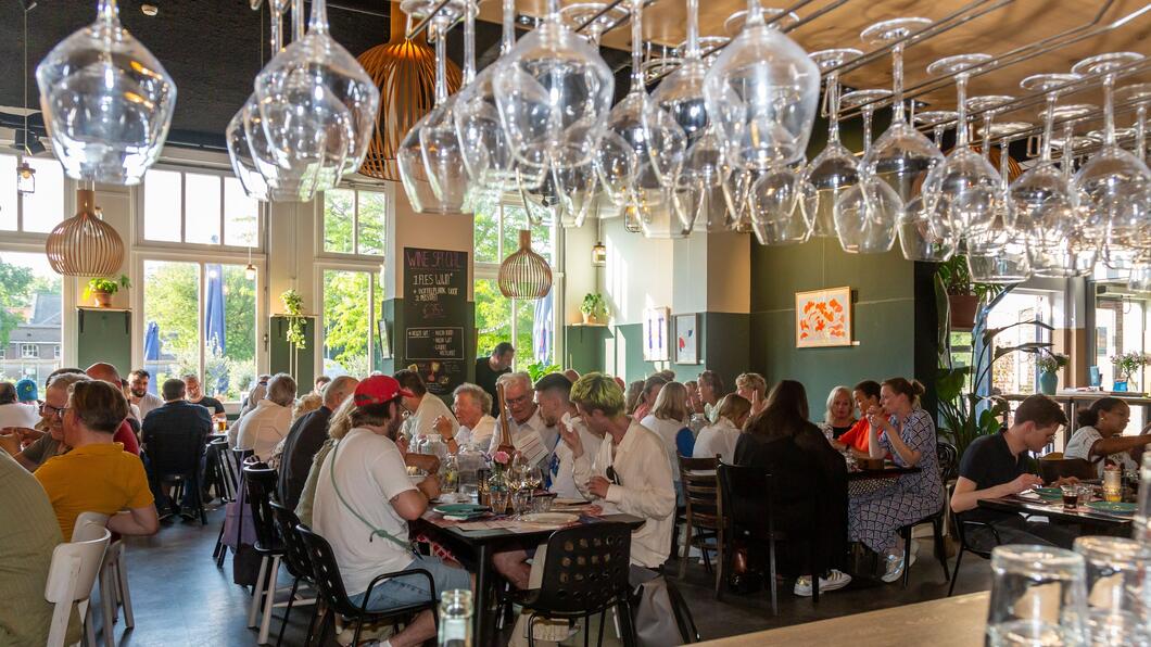 Foto van etende mensen aan lange tafels in De Oude Keuken. Foto door Nico Lute voor Castricum aan Tafel.
