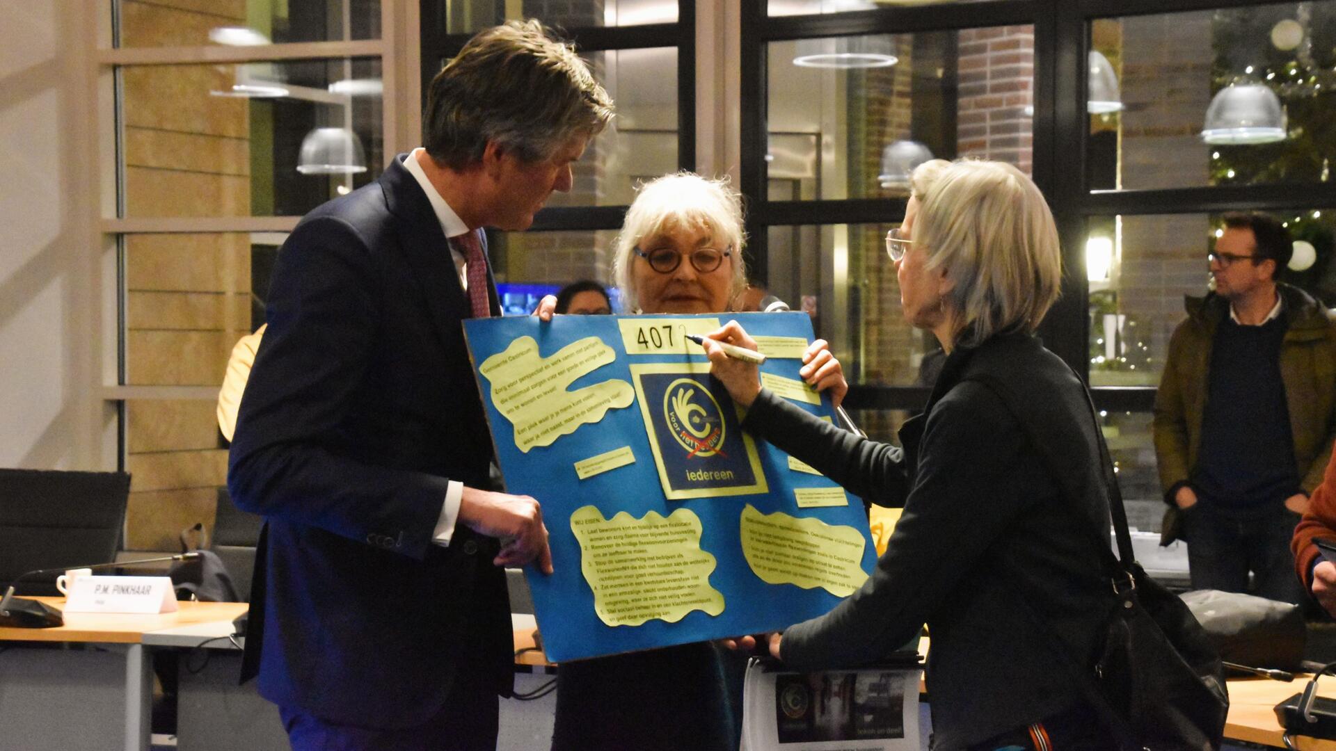 Niet wegstoppen maar huisvesten: twee vrouwen bieden burgemeester Mans van Castricum een petitie aan over het huisvesten van statushouders en spoedzoekers