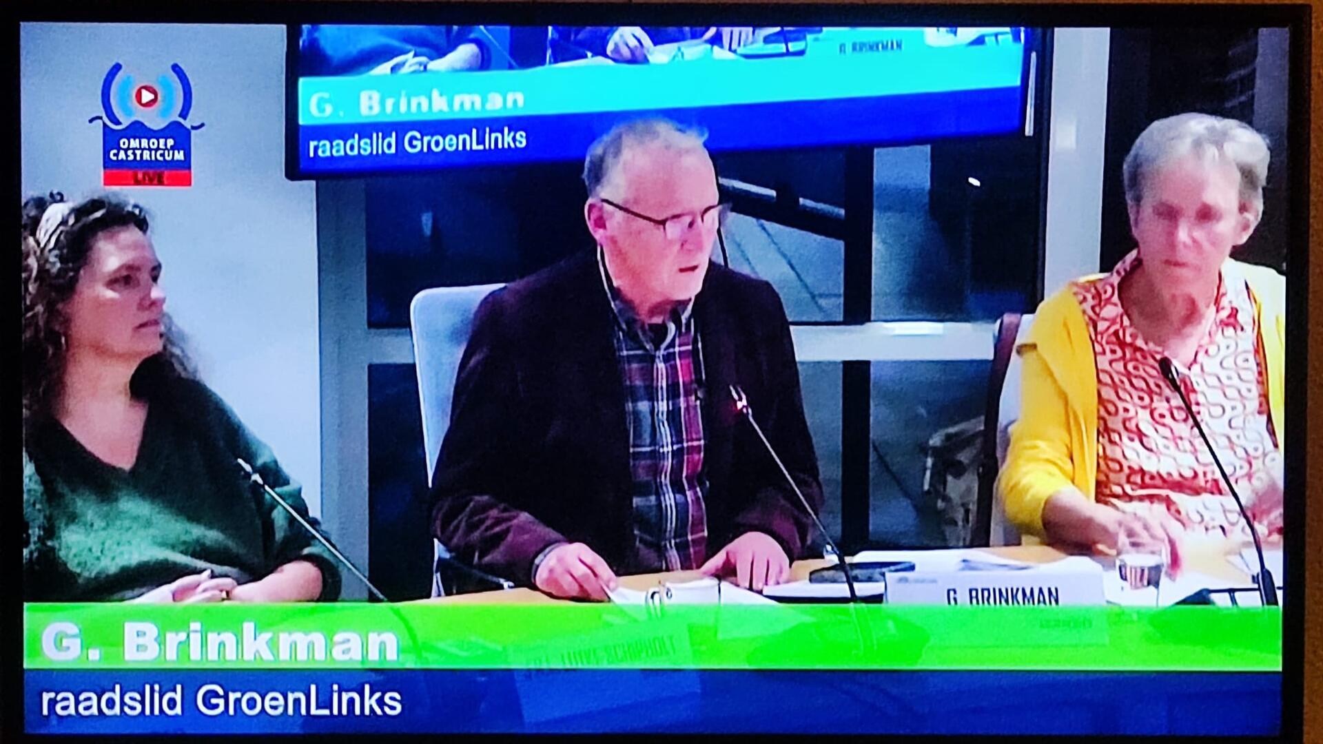 Foto van een beeldscherm waarop de raadsvergadering te zien is. In het midden van de foto zit GroenLinks fractievoorzitter Gerard Brinkman.